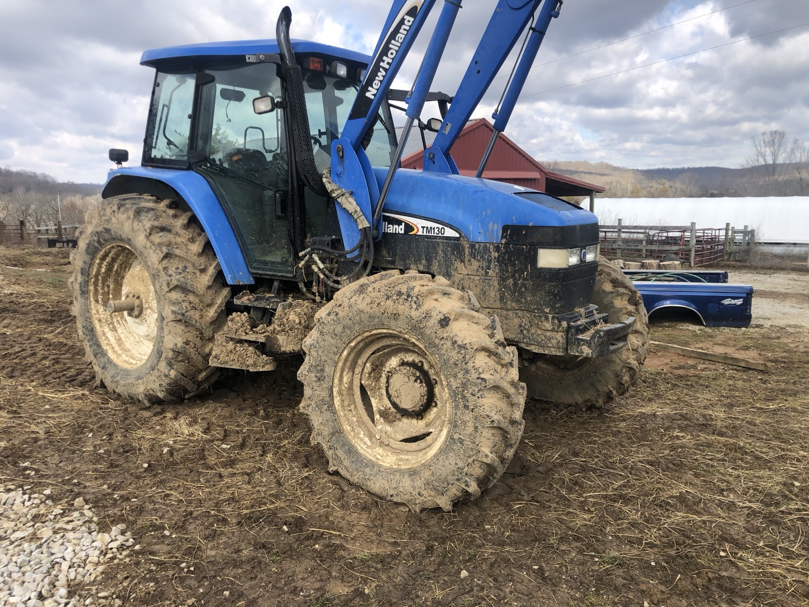 Blue tractor caked in mud before washing